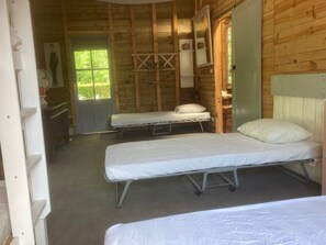Une chambre avec deux lits, un mur en bois, un miroir et une fenêtre.