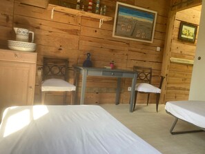 Une pièce de style cabane en bois, avec un lit, deux chaises, une table et un tableau accroché au mur.