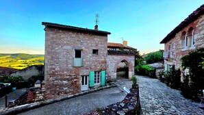 A narrow cobblestone street flanked by stone buildings with arched doorways and a small signboard. - Exceptional setting with Jacuzzi and cinema room for a suspended moment for 2 (Penne-d'Agenais)