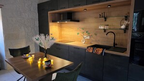 A modern kitchen with dark cabinetry, a wooden countertop, a built-in oven, and a sink. - Exceptional setting with Jacuzzi and cinema room for a suspended moment for 2 (Penne-d'Agenais)
