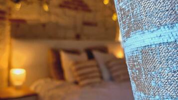 Een slaapkamer met een bed, nachtkastjes en een hanglamp.