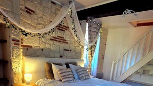 A bedroom with a bed, nightstand, and a staircase. - Exceptional setting with Jacuzzi and cinema room for a suspended moment for 2 (Penne-d'Agenais)