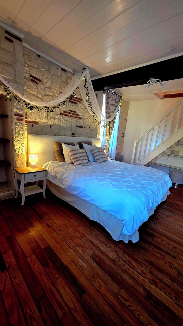 Un dormitorio con cama, mesita de noche y una escalera.