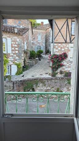 A courtyard with stone buildings, a cat walking, and a green railing.. Exceptional setting with Jacuzzi and cinema room for a suspended moment for 2