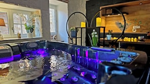 Un área de spa con un jacuzzi, detalles de madera y plantas en macetas.