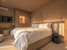 Un dormitorio moderno con una cama grande, mesitas de noche, un televisor de pantalla plana y estanterías empotradas.