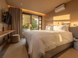 Un dormitorio moderno con una cama grande, una mesita de noche, un televisor y una ventana con cortinas.