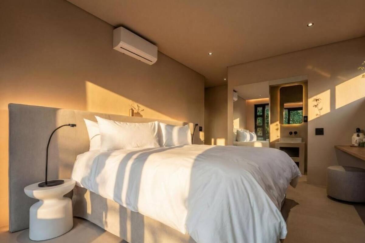 A modern bedroom with a bed, bedside table, and a small stool.