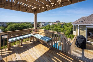Eine Holzterrasse mit einer Bank und einem Grill.