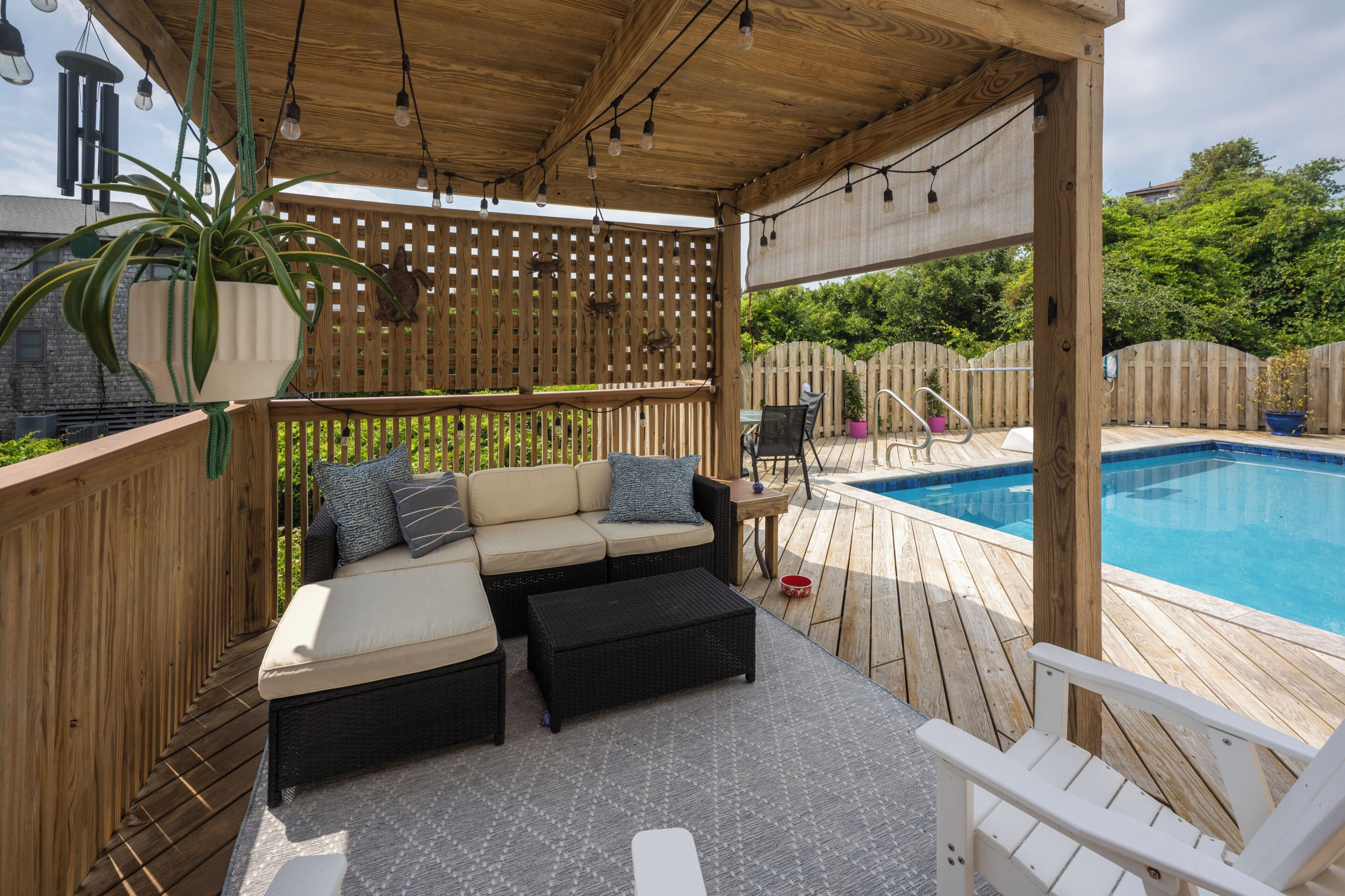 A covered outdoor area with a pool, wooden deck, and seating.
