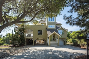 A two-story house with a garage, a covered porch, and a large tree in the front yard.