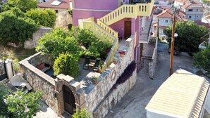 Ein mehrstöckiges Gebäude mit rosa Fassade, einer Treppe und einem kleinen Innenhof mit Blumentöpfen.
