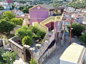 Ein mehrstöckiges Gebäude mit rosa Fassade, einer Treppe und einem kleinen Innenhof mit Blumentöpfen.