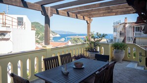 Eine Holzpergola mit Tisch und Stühlen mit Blick auf die Küste.