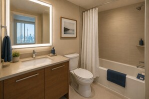 Ein modernes Badezimmer mit einem großen Spiegel, einem Waschbecken, einer Toilette und einer Badewanne.