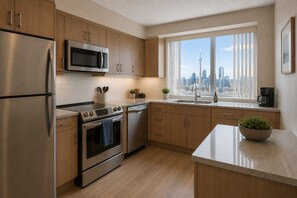 Eine moderne Küche mit Edelstahlgeräten, Holzschränken, einem großen Fenster mit Blick auf die Stadt und einer Arbeitsplatte mit einer Schüssel frischem Grünzeug.