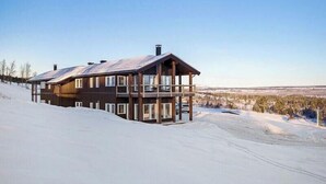 A multi-story wooden building with balconies, situated on a snowy slope.