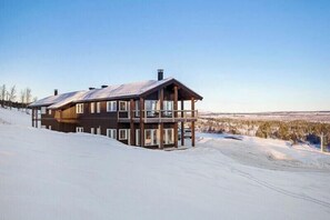 A multi-story wooden building with balconies, situated on a snowy slope.