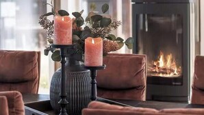 A modern interior with a fireplace, a chandelier, and a table with candles.