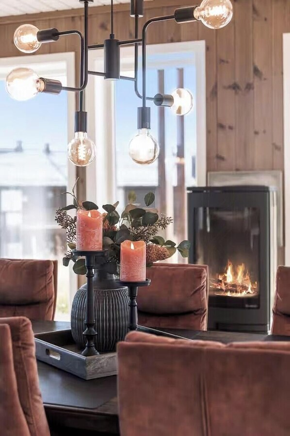 A modern interior with a fireplace, a chandelier, and a table with candles.