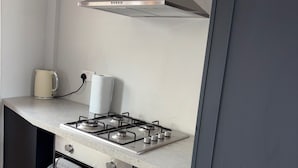 Una cocina con estufa a gas, horno y hervidor sobre la encimera.