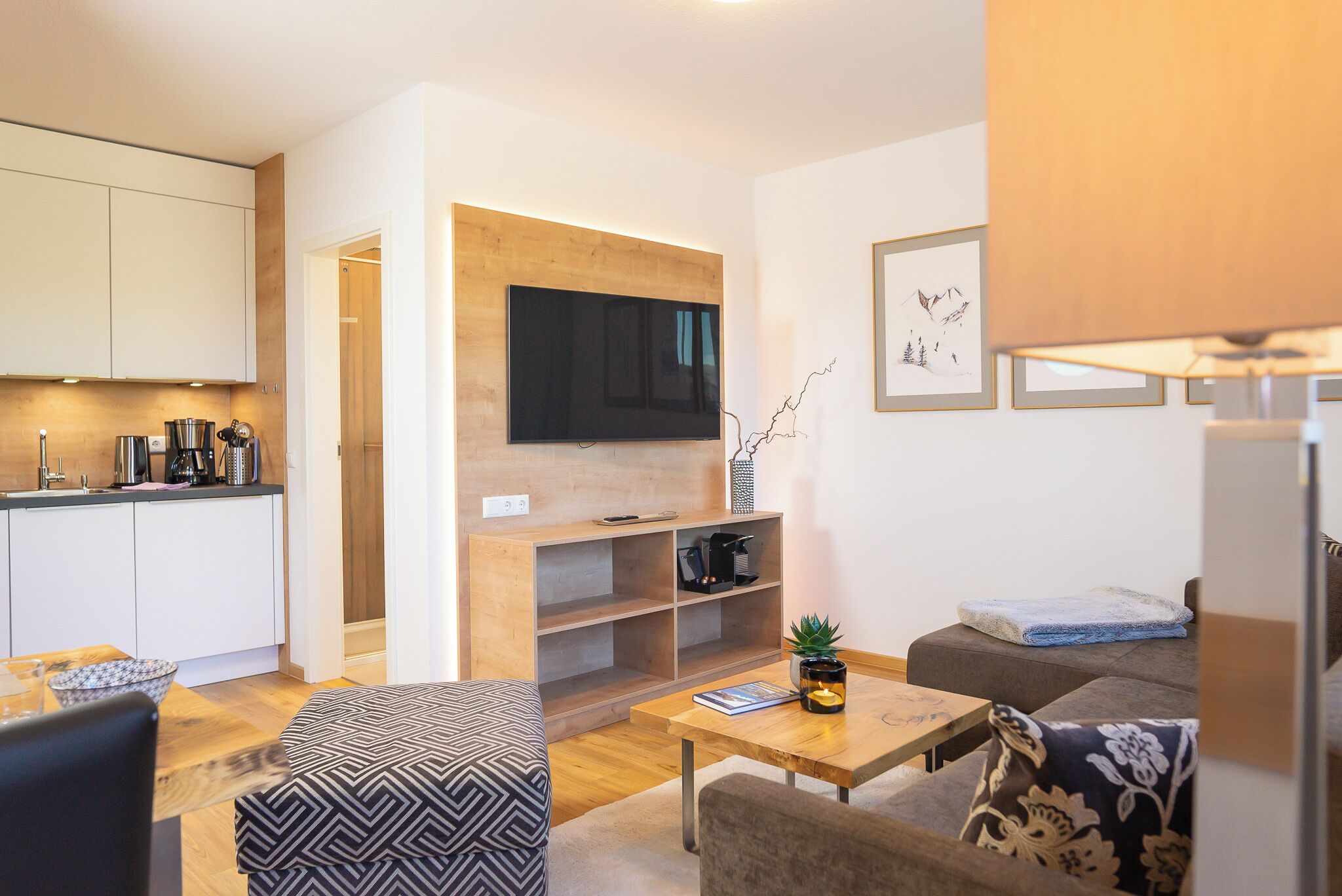 A modern living room with a flat-screen TV, a coffee machine, a bookshelf, and a sofa.