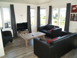 Un soggiorno con un divano, un tavolino, una TV e una poltrona.