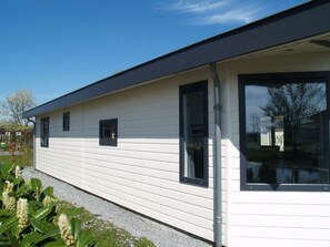 A modern single-story building with horizontal siding, large windows, and a flat roof. - Holiday Home in Dordrecht With Terrace (Dordrecht)