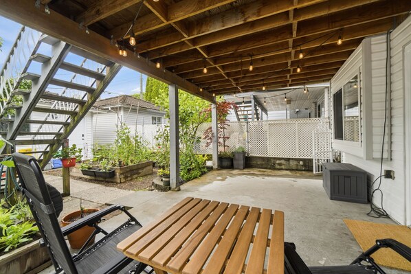 A covered patio with a wooden table, chairs, and a ladder.