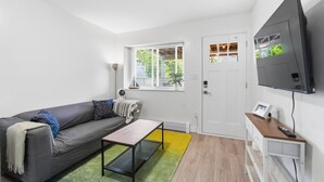 Una sala de estar moderna con un sofá, una mesa de centro, un televisor y una ventana con persianas.