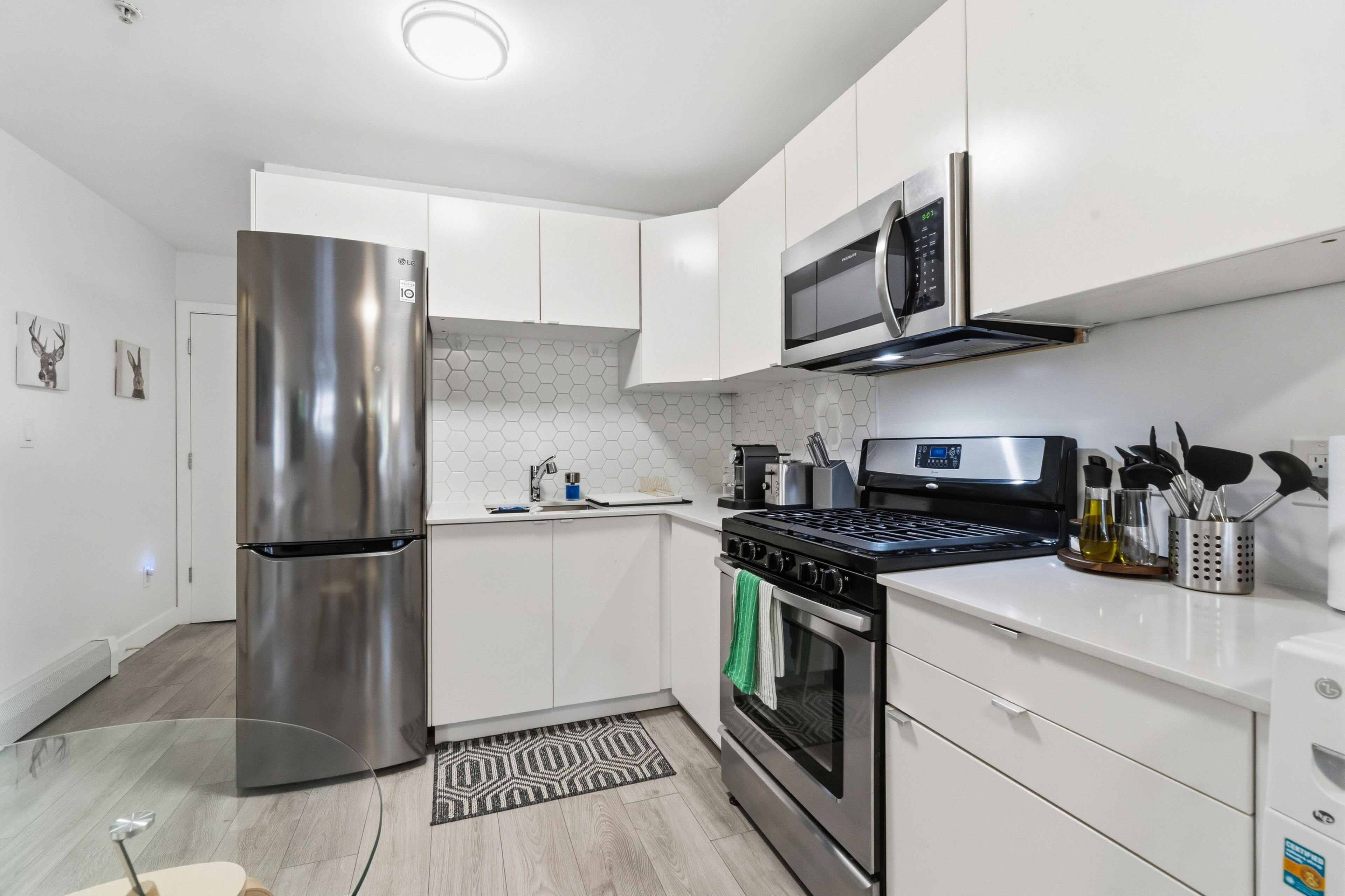 A modern kitchen with stainless steel appliances, white cabinetry, and a microwave.