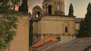 A narrow alleyway with a building featuring a dome and bell tower, surrounded by trees and a rustic atmosphere. - DRO Hotel (Kutaisi)