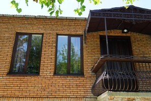 A brick building with two windows and a balcony with a wrought iron railing. - DRO Hotel (Kutaisi)