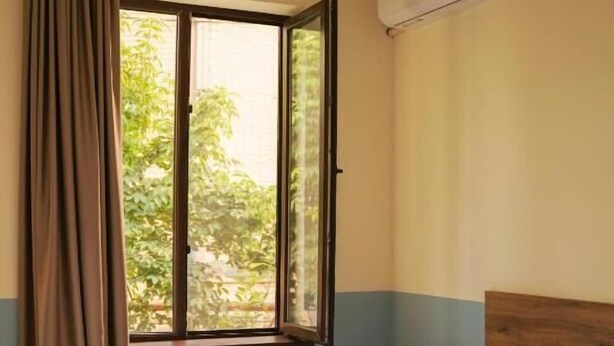A hotel room with a bed, a window with curtains, and an air conditioning unit. - DRO Hotel (Kutaisi)