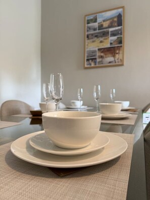 A dining table with white bowls and glasses, a framed collage on the wall, and a neutral-toned room. - Stable Cottage - with free parking! (Woodborough)