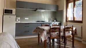 Una cocina compacta con armarios grises, un microondas y una mesa con sillas.