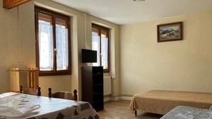 Una habitación con una mesa, dos camas, un televisor y un cuadro en la pared.