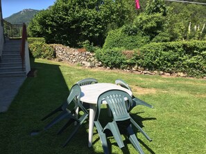 Eine Terrasse mit Tisch und Stühlen, eine Steinmauer und ein Berg im Hintergrund.