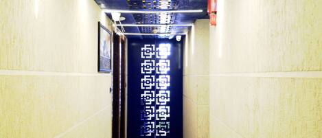 A hallway with a patterned ceiling, a door with a digital display, and a marble floor.