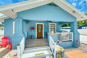 Ein blaues Haus mit Veranda, einem roten Sessel, einem Blumentopf und einem Willkommensschild.