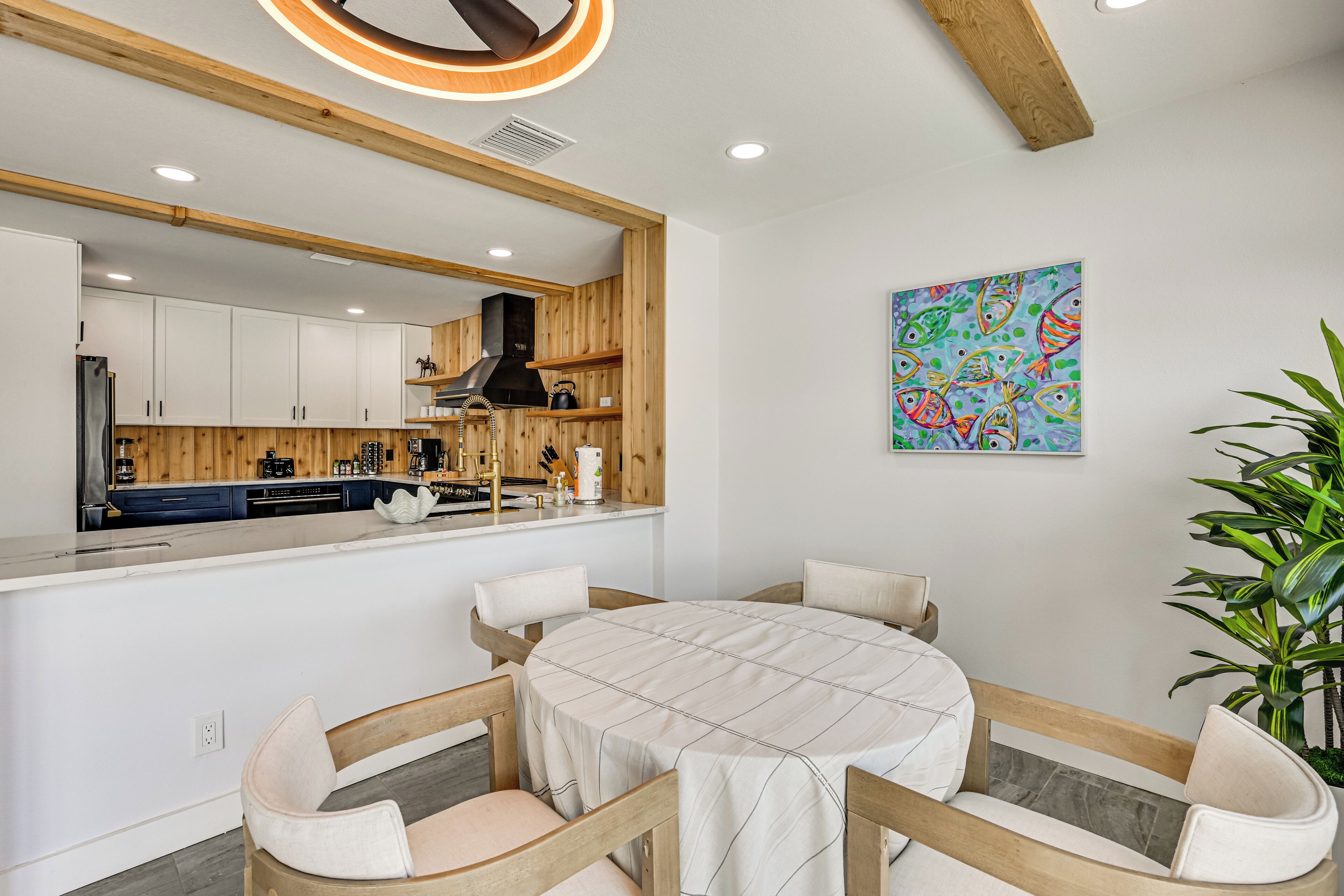 Una cocina moderna con armarios de madera, una isla central y una zona de comedor con una mesa redonda y sillas.