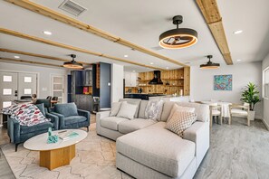 Ein modernes Wohnzimmer mit einem Ecksofa, einem Couchtisch und einem Essbereich mit einem kleinen Tisch und Stühlen.