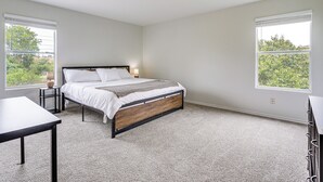 Een slaapkamer met een bed, een tafel en twee ramen.