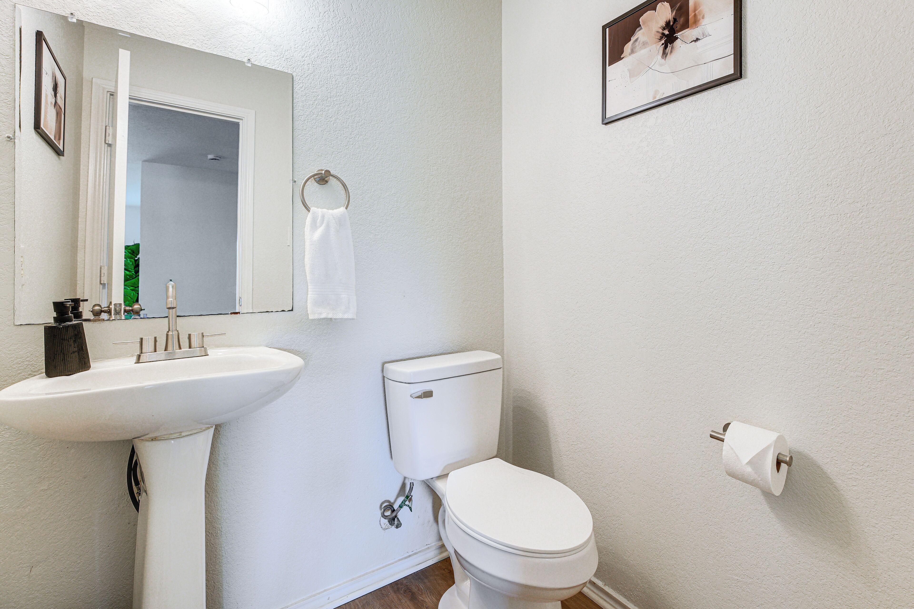 A bathroom with a white sink, toilet, and a towel hanging on the wall.