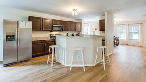 Een moderne keuken met een centraal eiland, roestvrijstalen apparatuur en houten keukenkastjes.