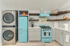A compact kitchen with a washing machine, a teal refrigerator, a stove, and a coffee maker. - 1 Mi to Beach & Bay! Group Getaway in Galveston (Galveston)