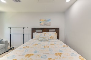 A neatly made bed with a patterned bedspread, a wooden headboard, and a wall-mounted artwork above. - 1 Mi to Beach & Bay! Group Getaway in Galveston (Galveston)