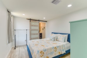 Quarto com cama, guarda-roupa, porta de correr e luz no teto.