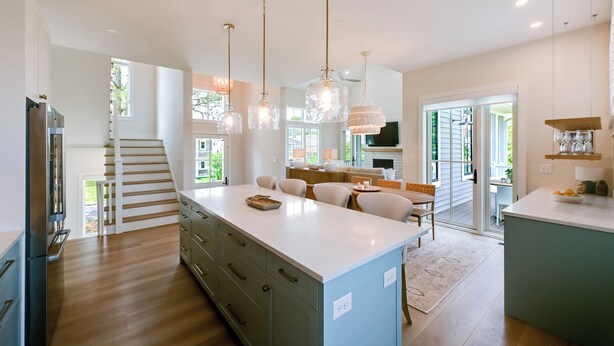 A modern kitchen with a central island, pendant lights, and a staircase leading to an upper level. - Walk to Beaches: Family Getaway in Bethany Beach! (Bethany Beach)