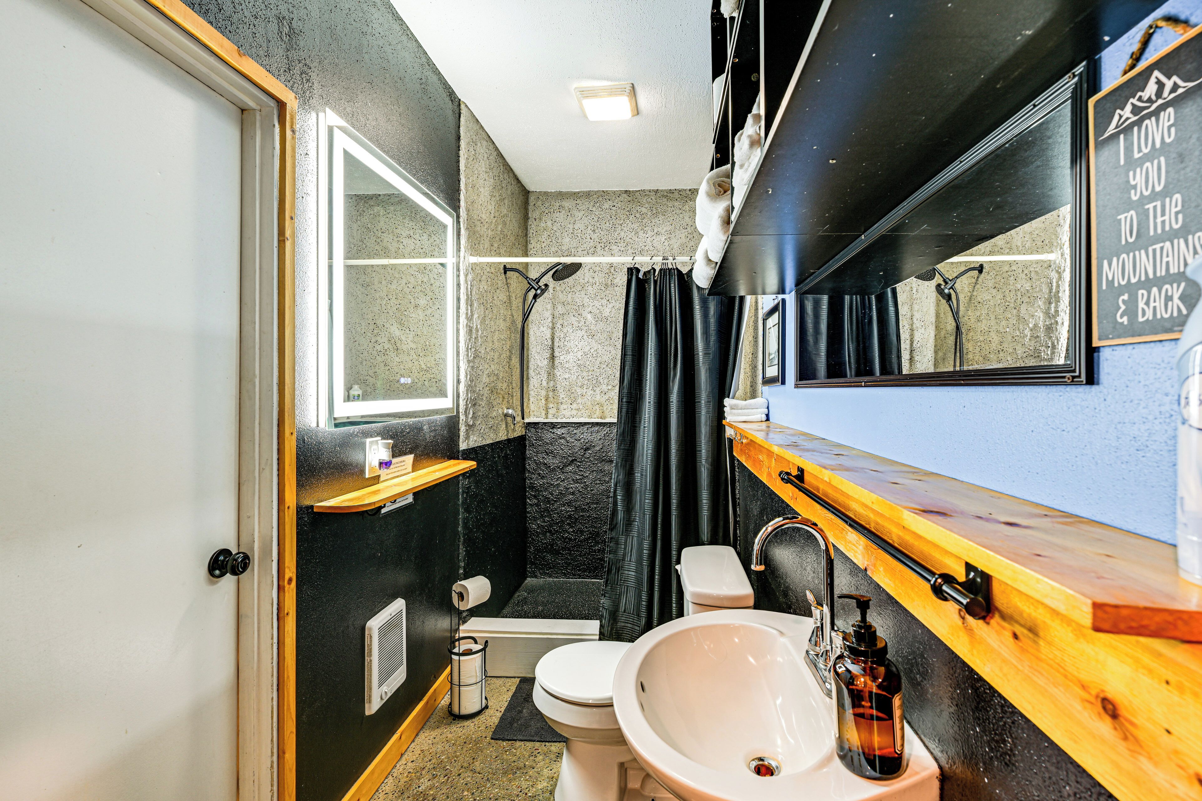 A compact bathroom with a shower, toilet, sink, and a mirror.